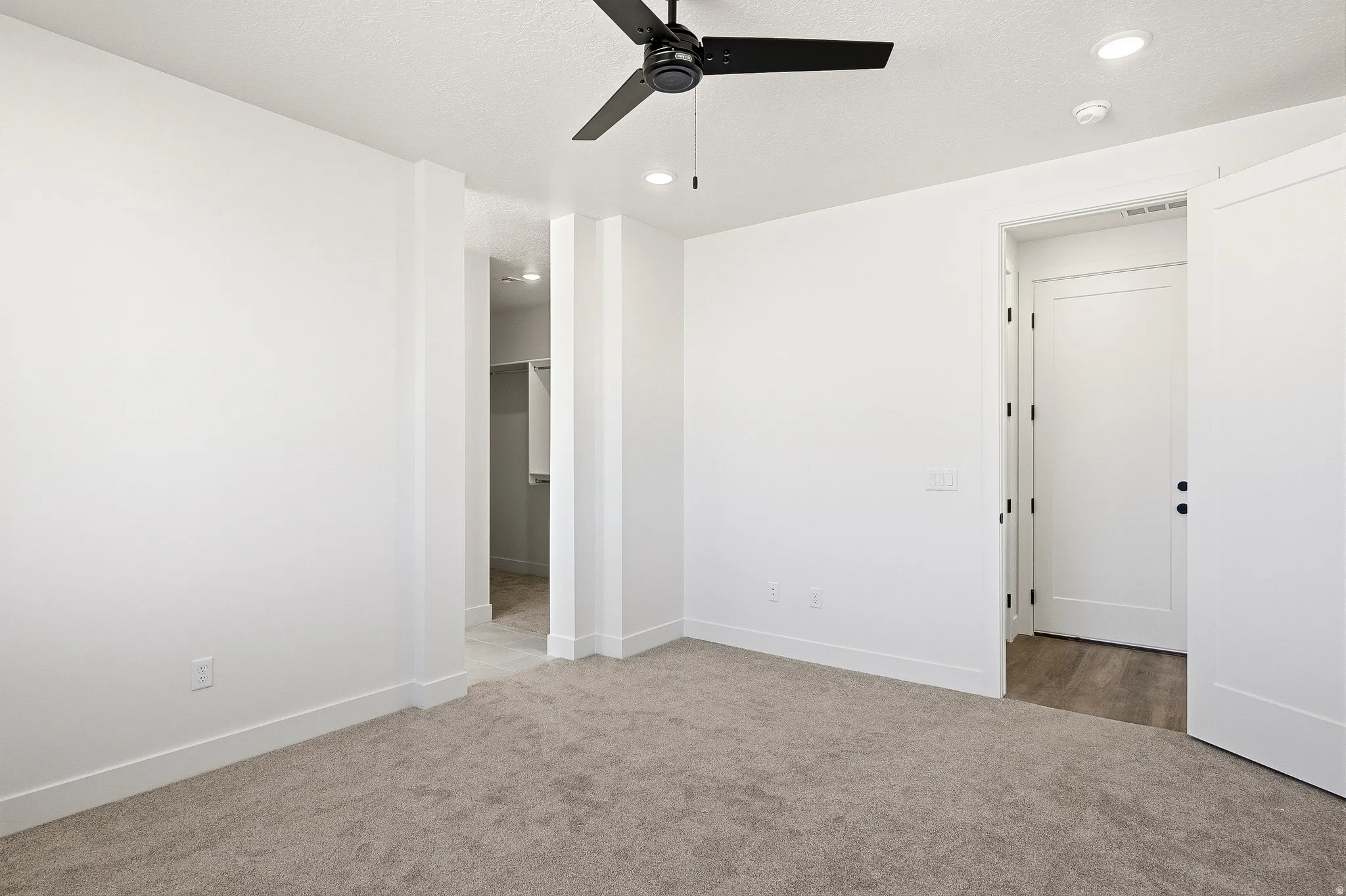 Carpeted interior space featuring a matte black ceiling fan, recessed lighting, and a closet with built-in shelving
