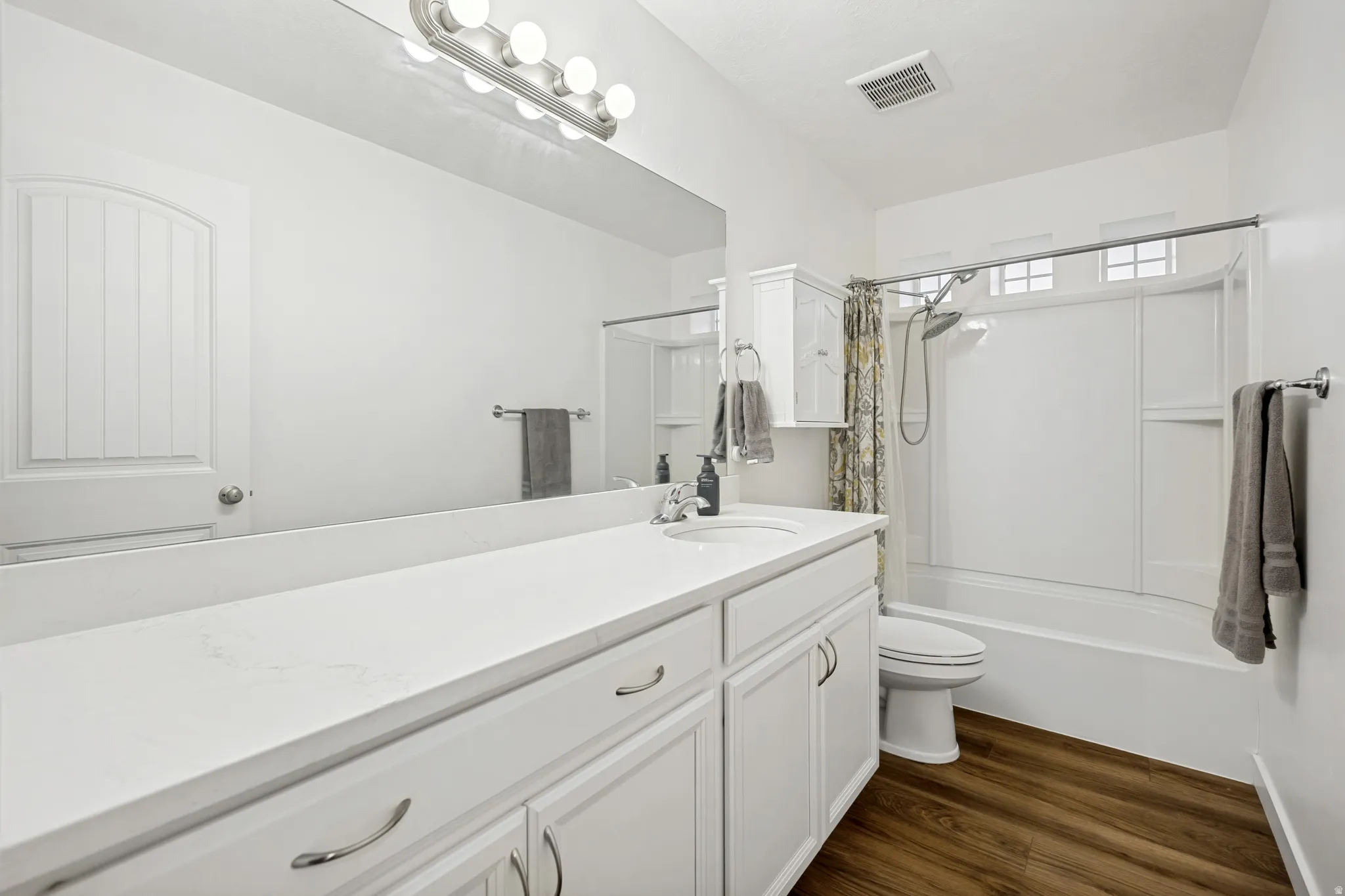 Bathroom featuring a white vanity with an integrated sink, polished chrome hardware, and a large wall mirror