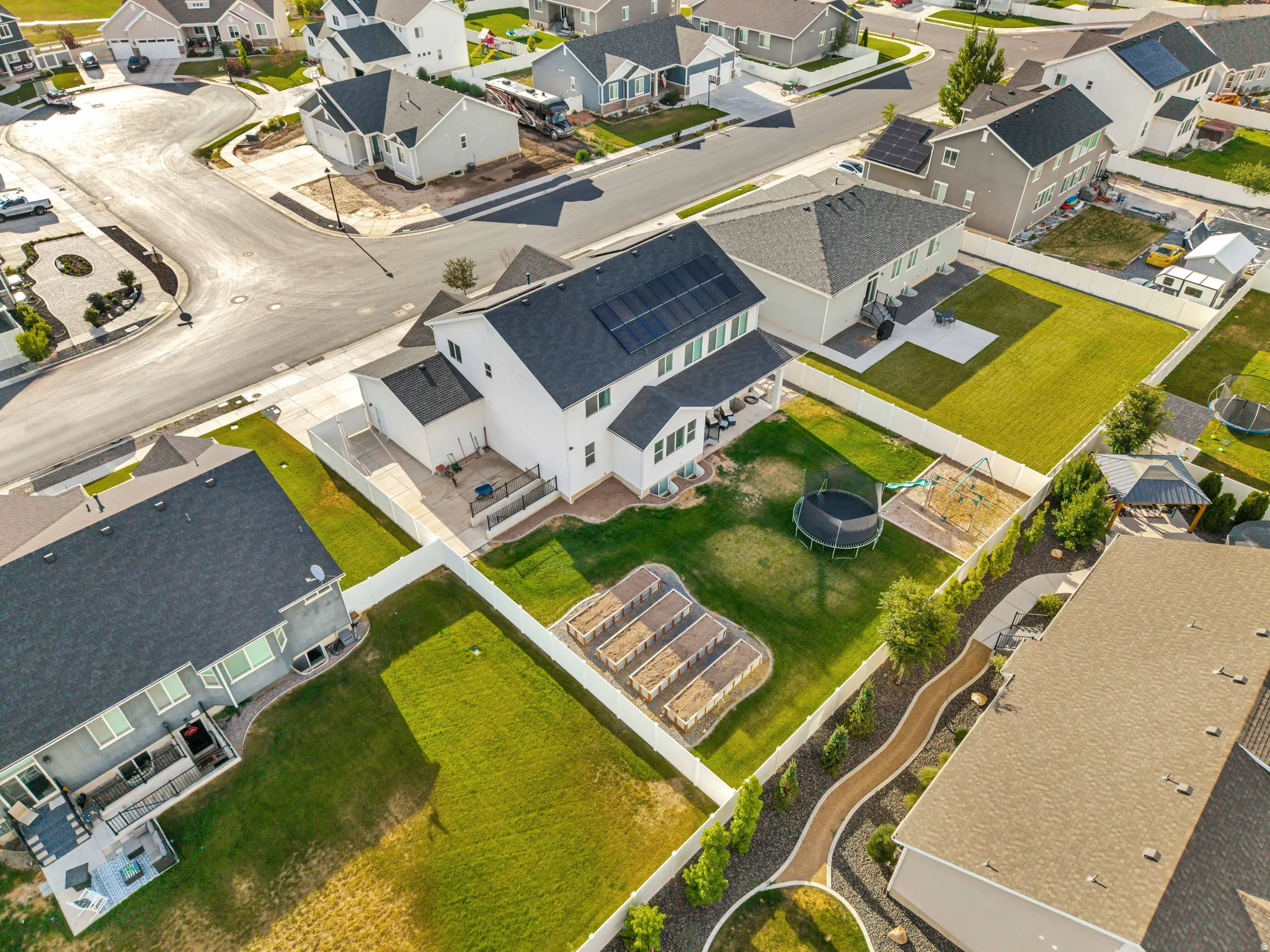 Expansive backyard featuring a lush lawn, raised garden beds, and mature perimeter landscaping