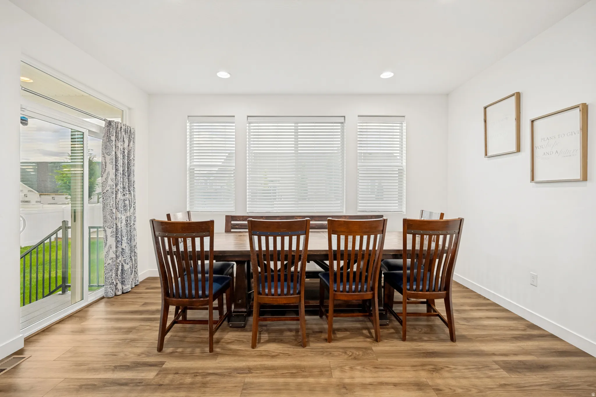 Bright interior space featuring wood-finish flooring, recessed lighting, and three large windows with horizontal blinds