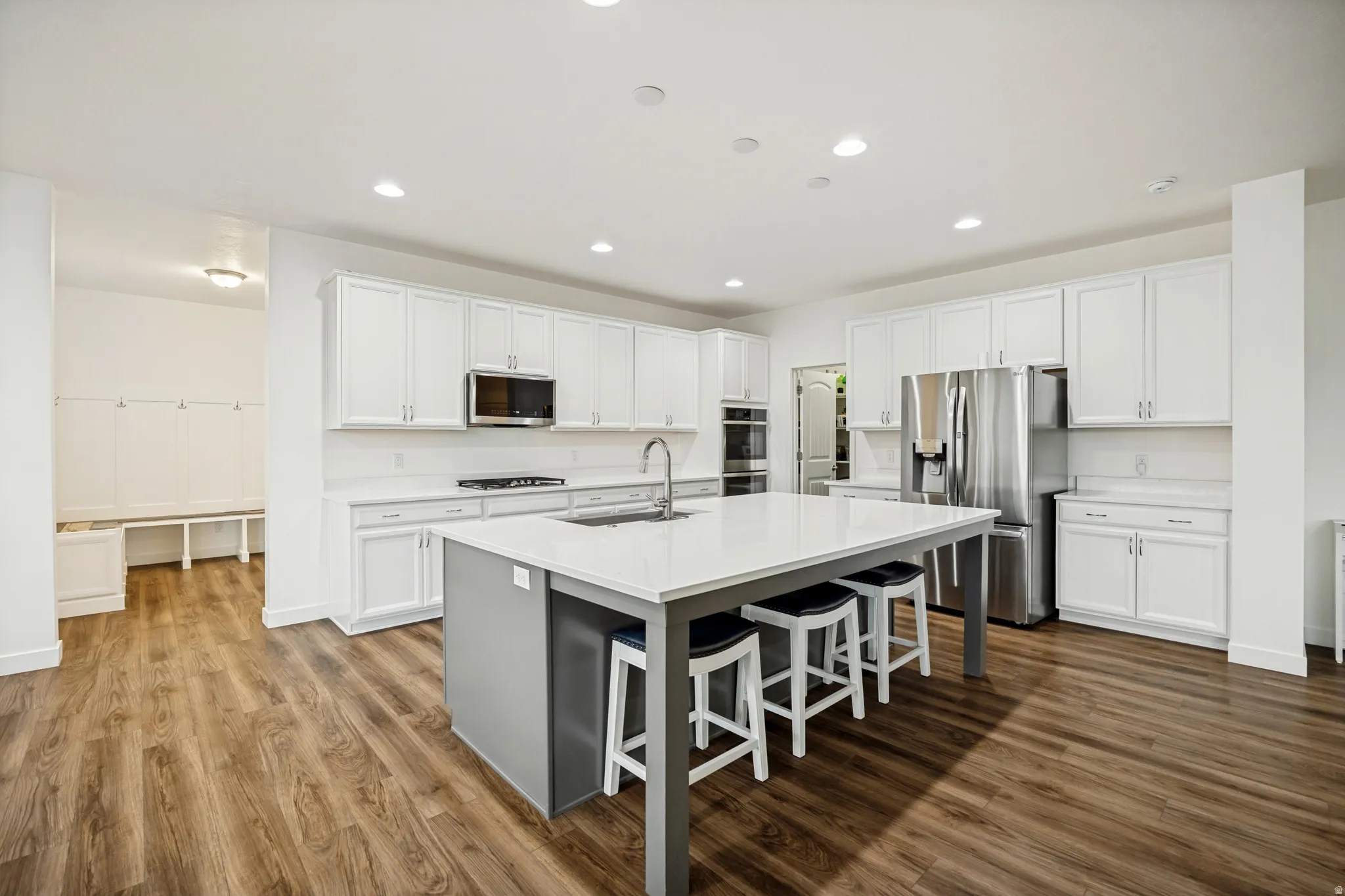 Spacious kitchen featuring an expansive central island with seating, extensive white cabinetry, and wood-finish flooring