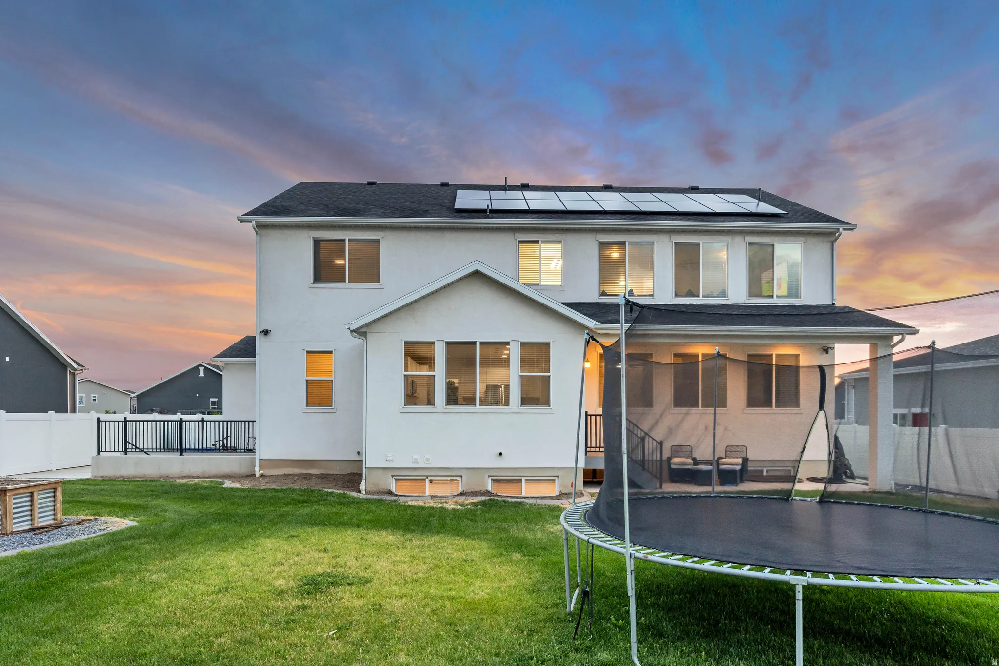 Two-story residence featuring a white stucco exterior, dark roof, and solar panels