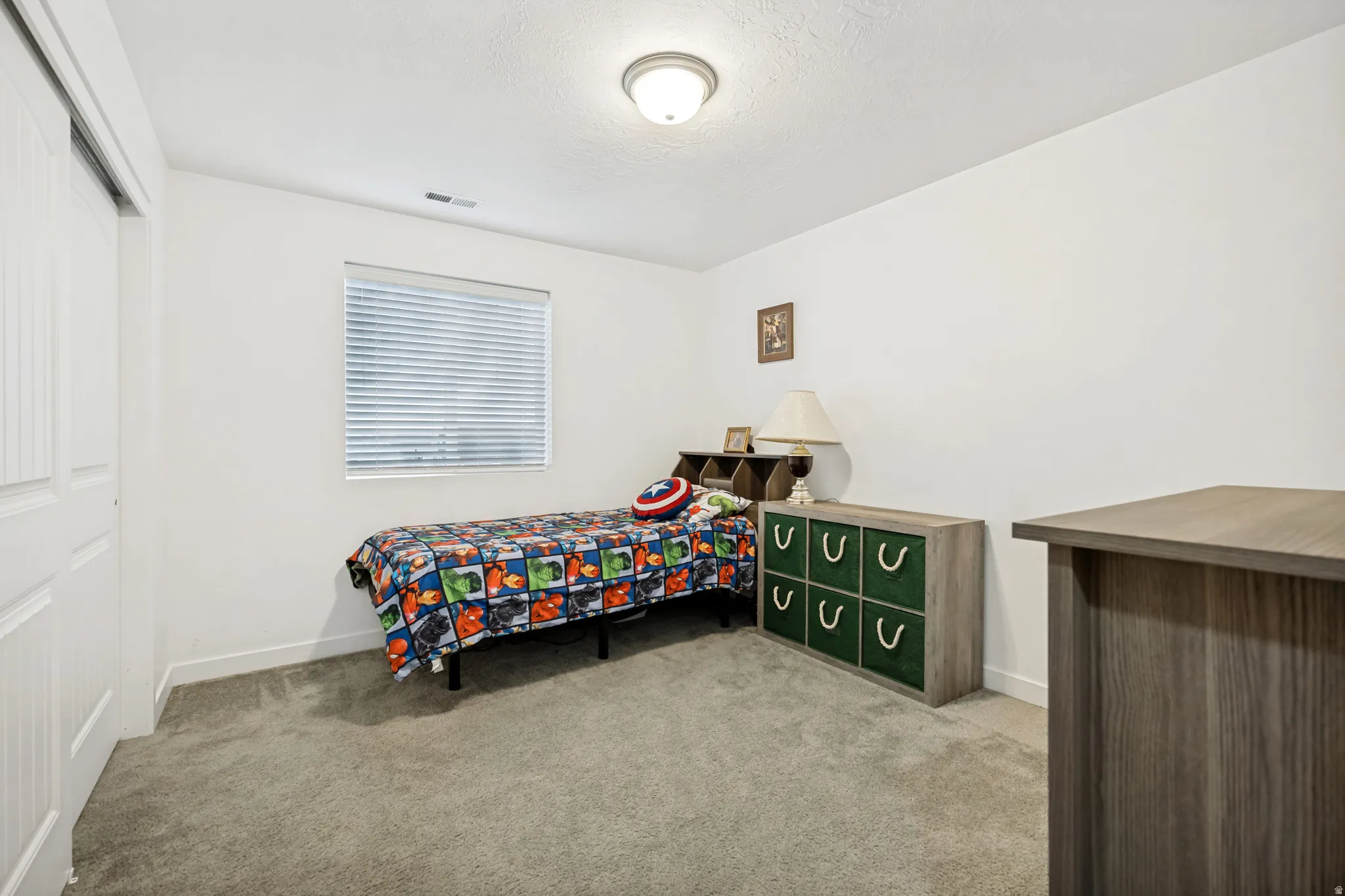 Carpeted room featuring a single window with blinds, white walls, and a sliding closet door