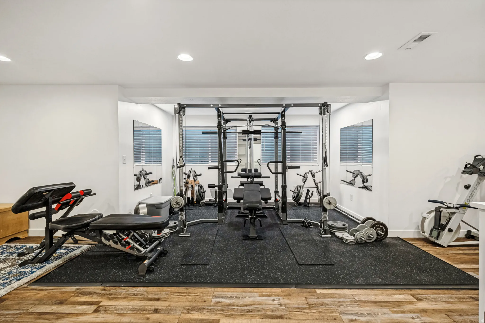 Dedicated fitness space featuring wood-finish flooring, recessed lighting, and white walls