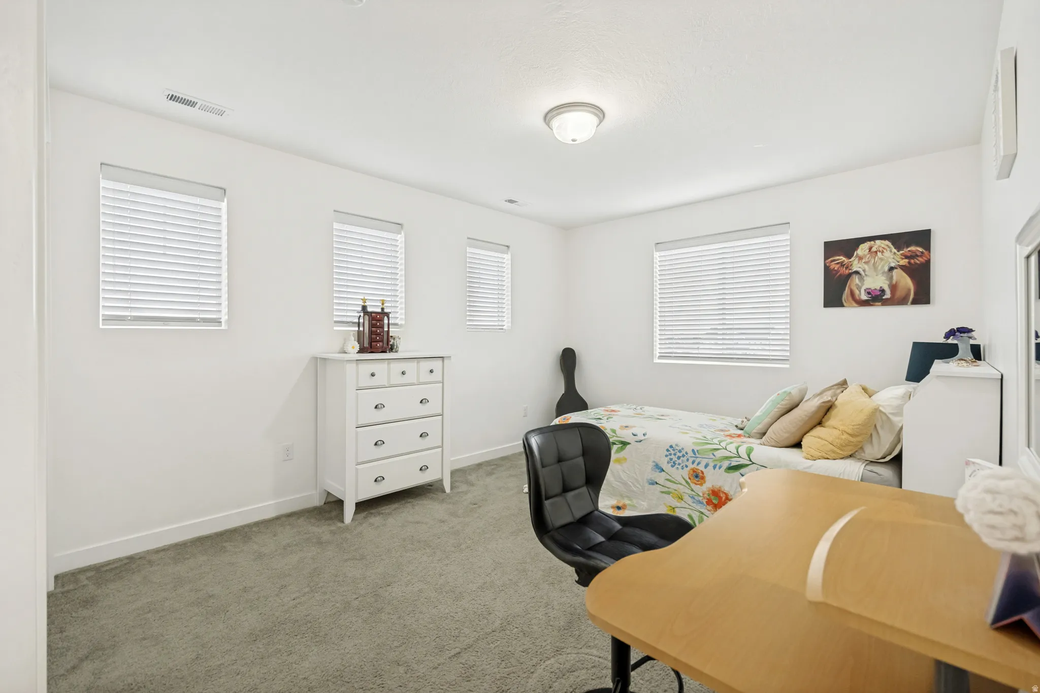Room featuring neutral-toned carpeting, multiple windows with white blinds, and a flush-mount ceiling light
