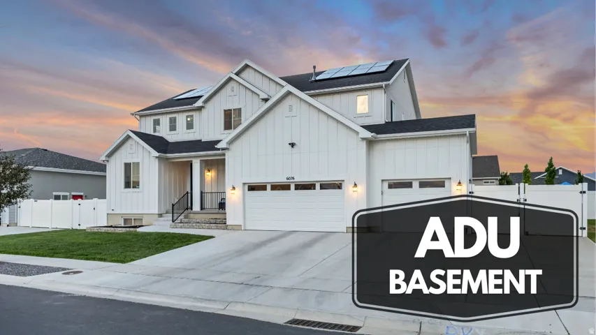 White exterior with board and batten siding, black roof, solar panels, and a concrete driveway