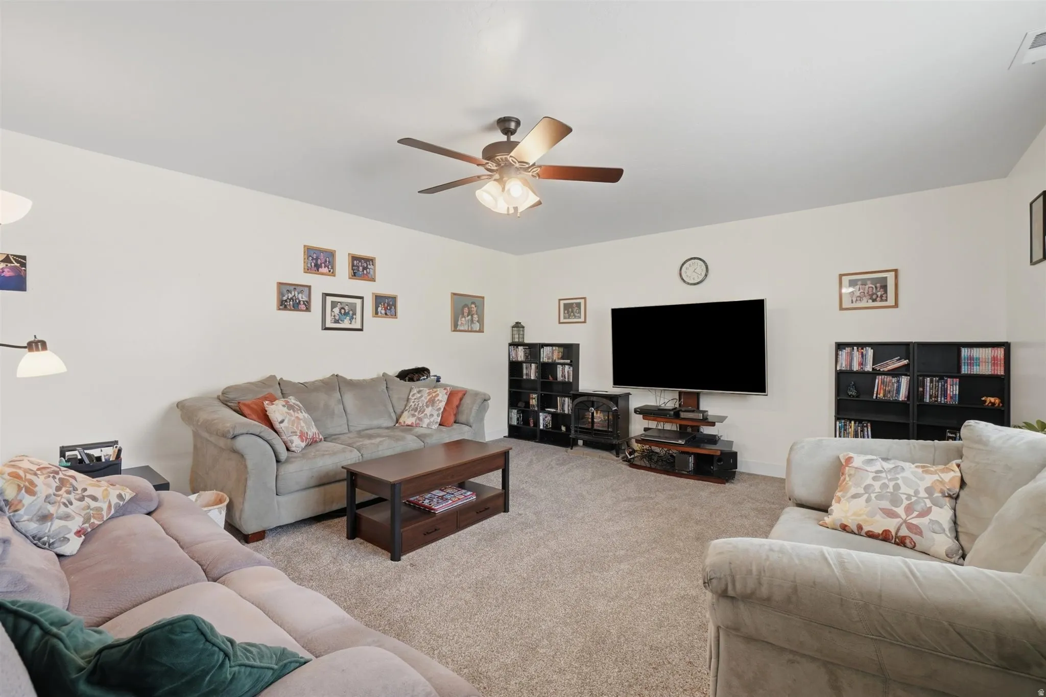 Spacious room featuring neutral wall tones, carpeted flooring, and a ceiling fan with integrated lighting