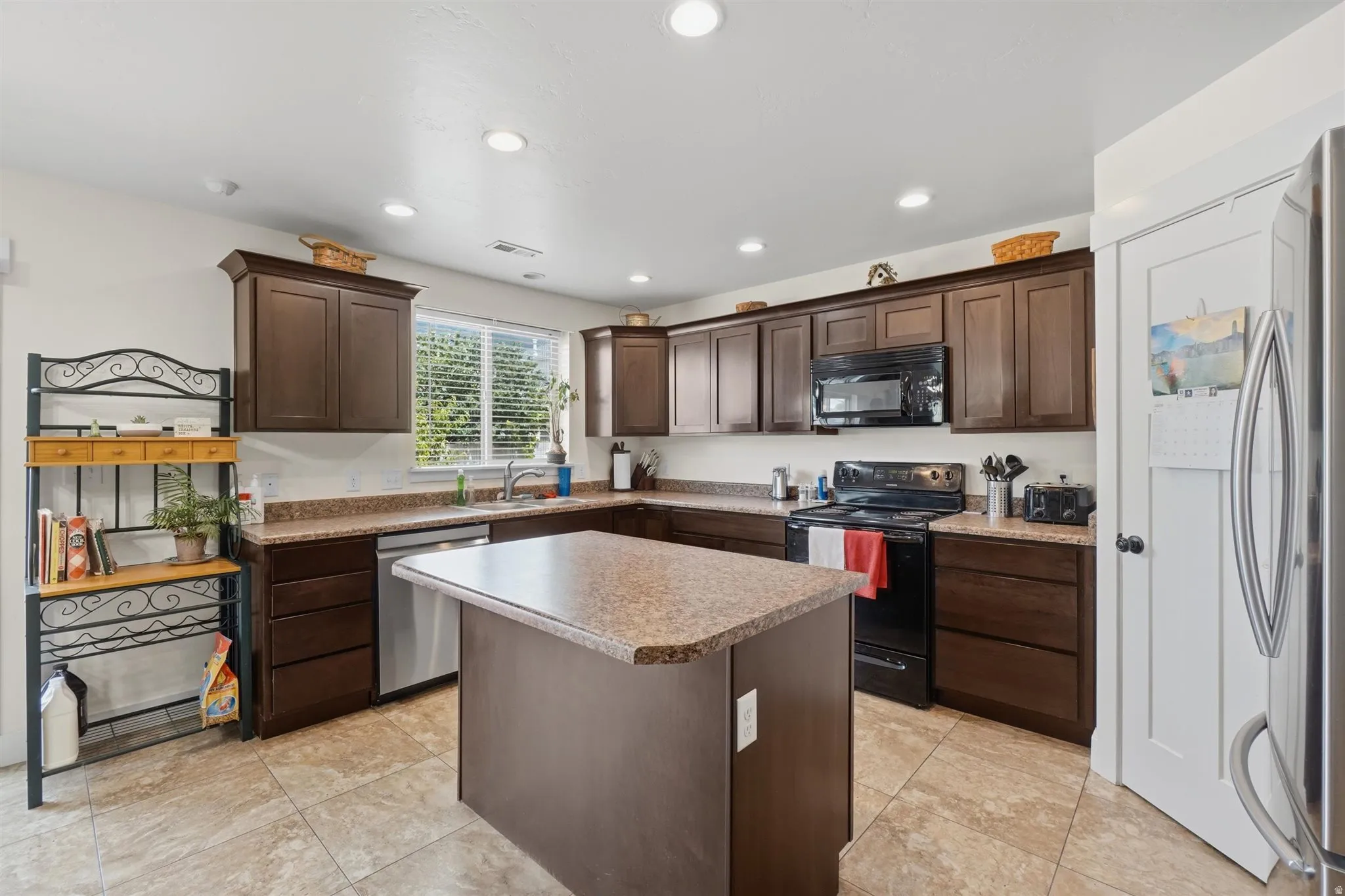 Kitchen featuring a central island, recessed lighting, wood-finish cabinetry, tile flooring, and a window with blinds