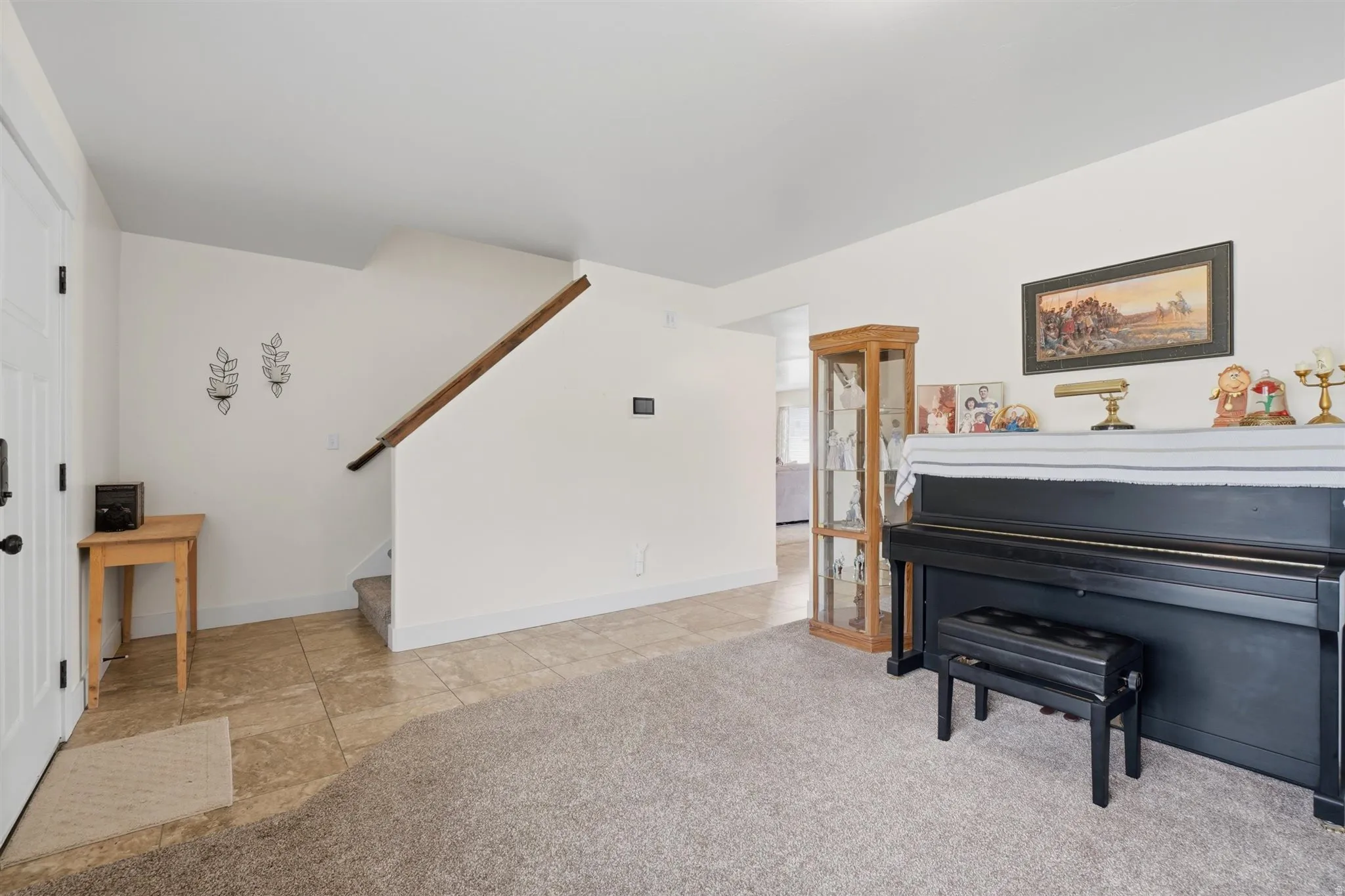 Entryway featuring a white paneled door, a staircase with wood railing, and a combination of carpet and natural stone-look tile flooring