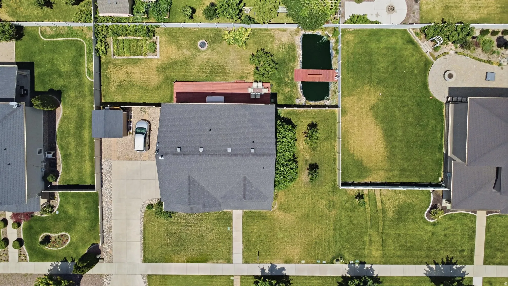 Property featuring a dark shingle roof, a concrete driveway, and a gravel parking area