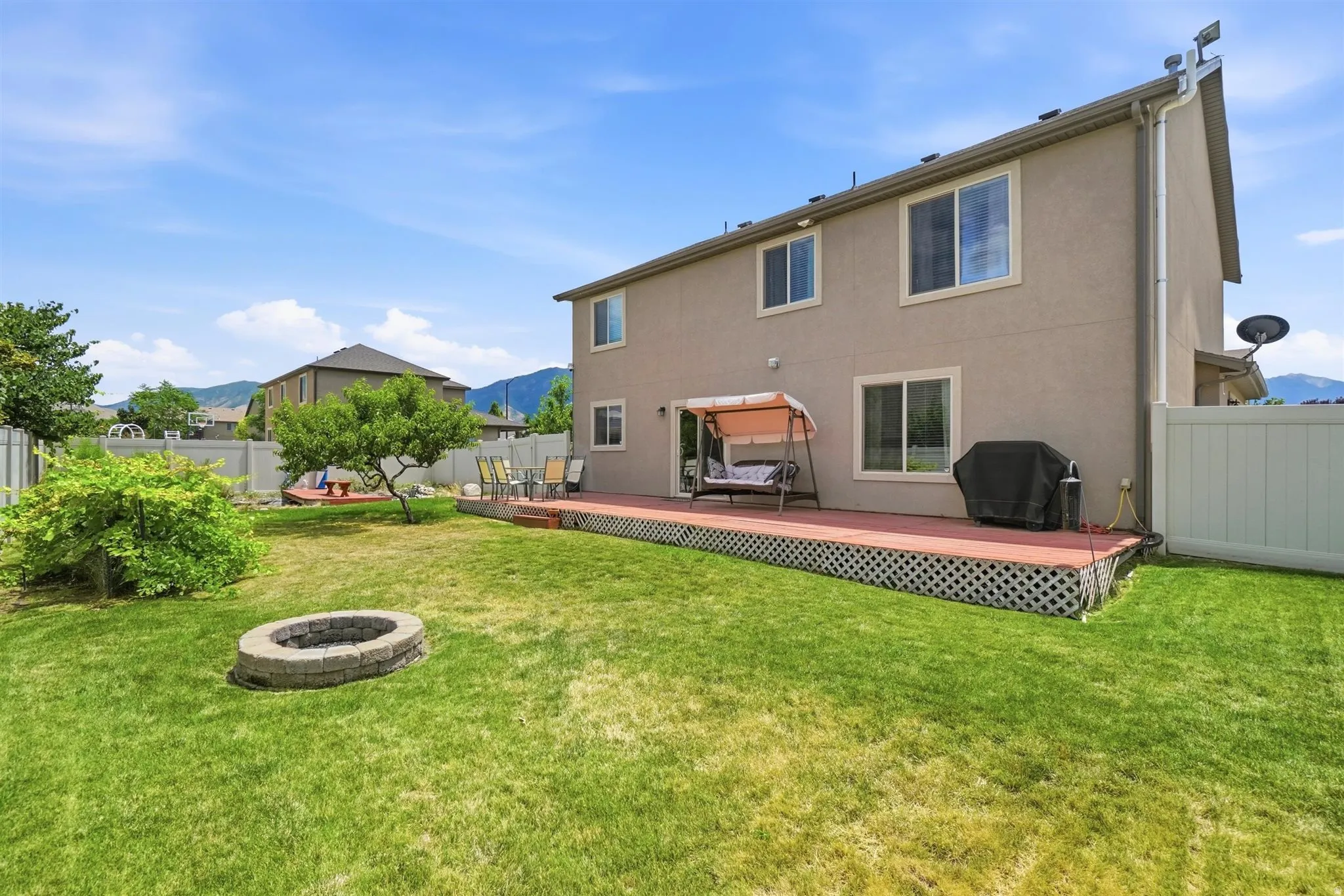 Expansive grassy yard with a stone-surrounded fire pit