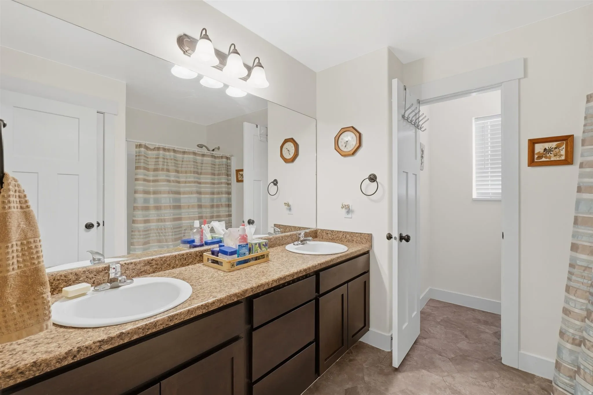 Double vanity with integrated sinks, granite-finish countertop, and dark wood cabinetry