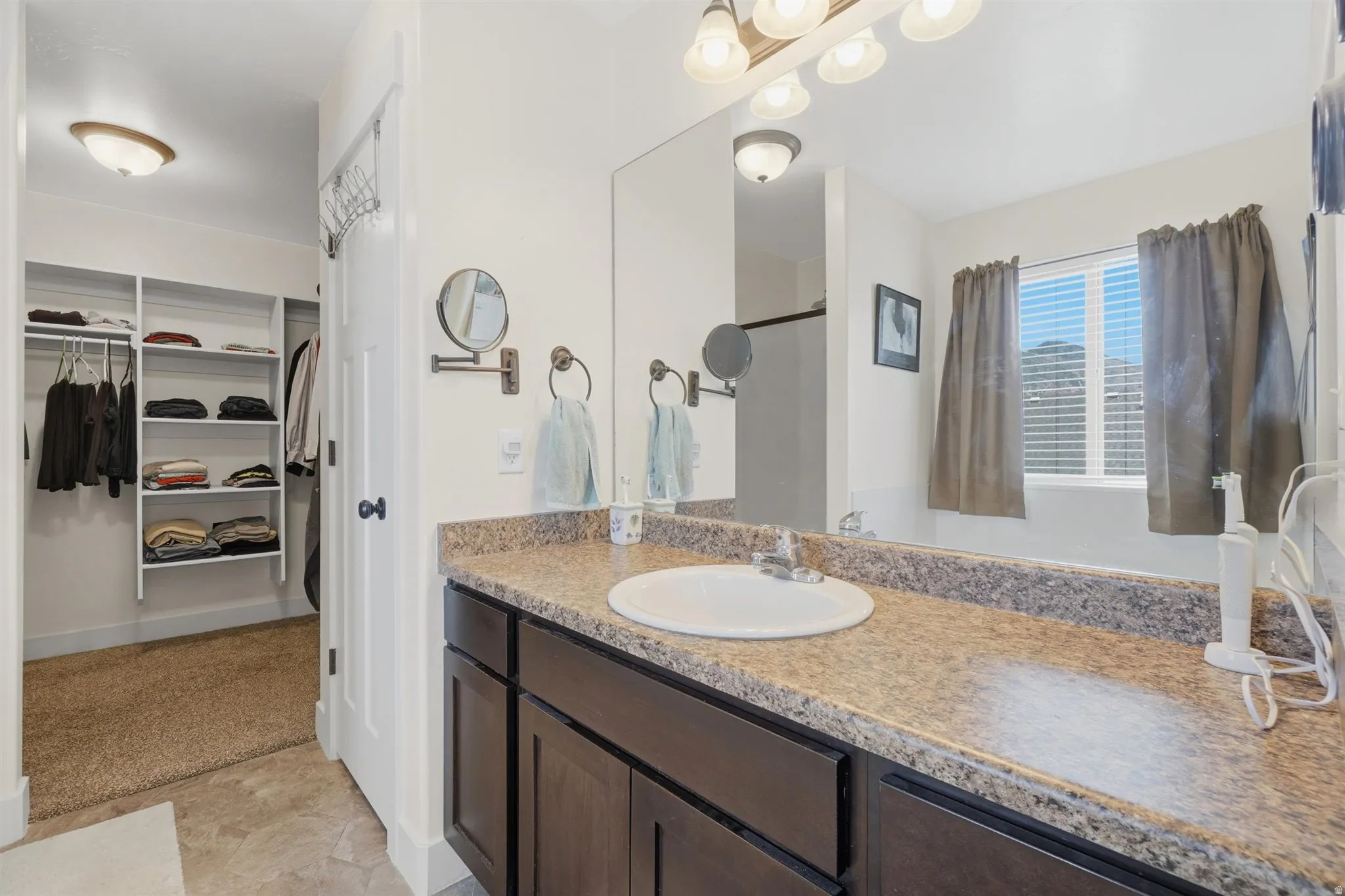 Bathroom vanity featuring a single basin sink, laminate countertop, and dark wood cabinetry