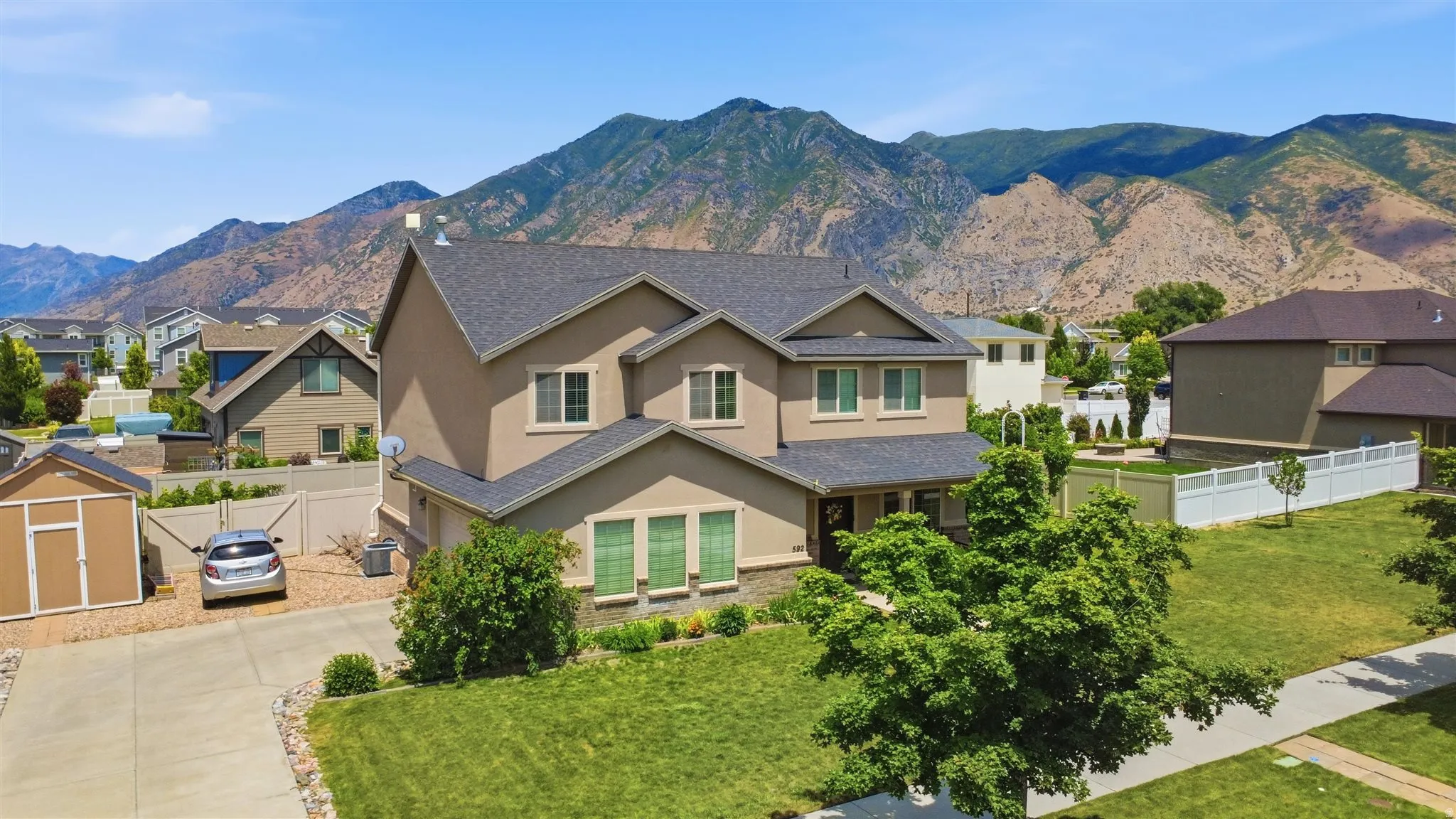 Two-story stucco home with a dark shingle roof and a stone accent facade
