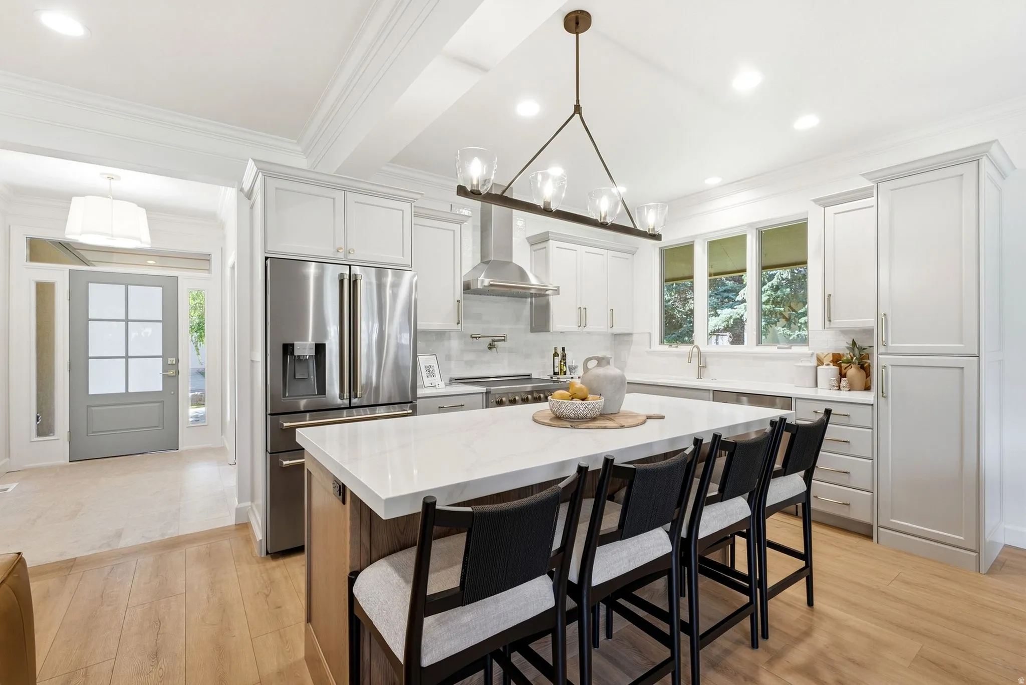Spacious kitchen featuring an expansive island, stainless steel appliances, light wood-finish flooring, white cabinetry, and recessed lighting