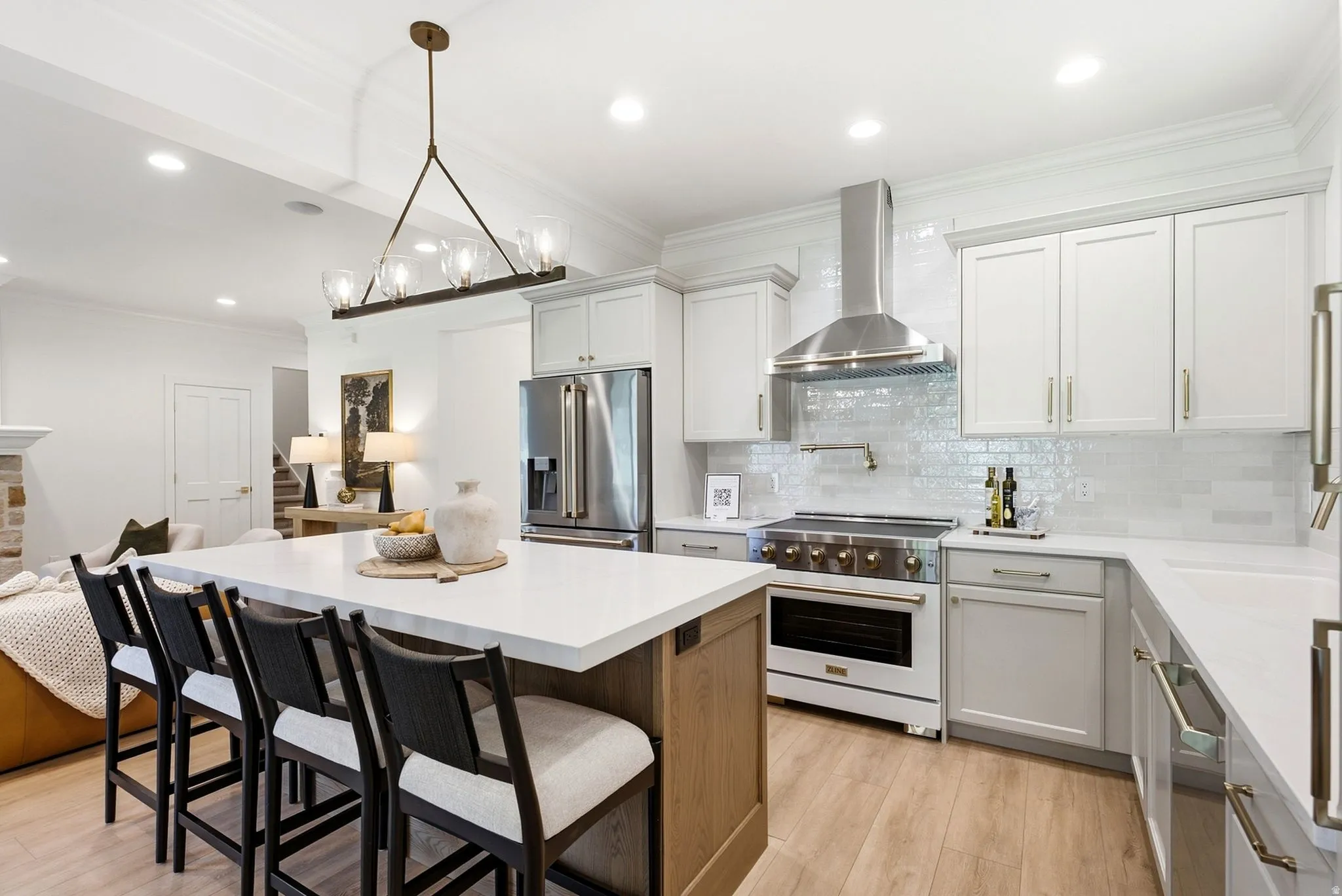 Gourmet kitchen with a large island, wood-finish flooring, stainless steel appliances, white cabinetry, and recessed lighting
