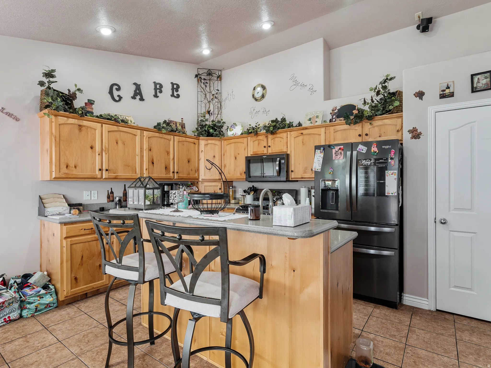 Kitchen featuring light wood cabinetry, stone-finish countertops, stainless steel appliances, and tile flooring
