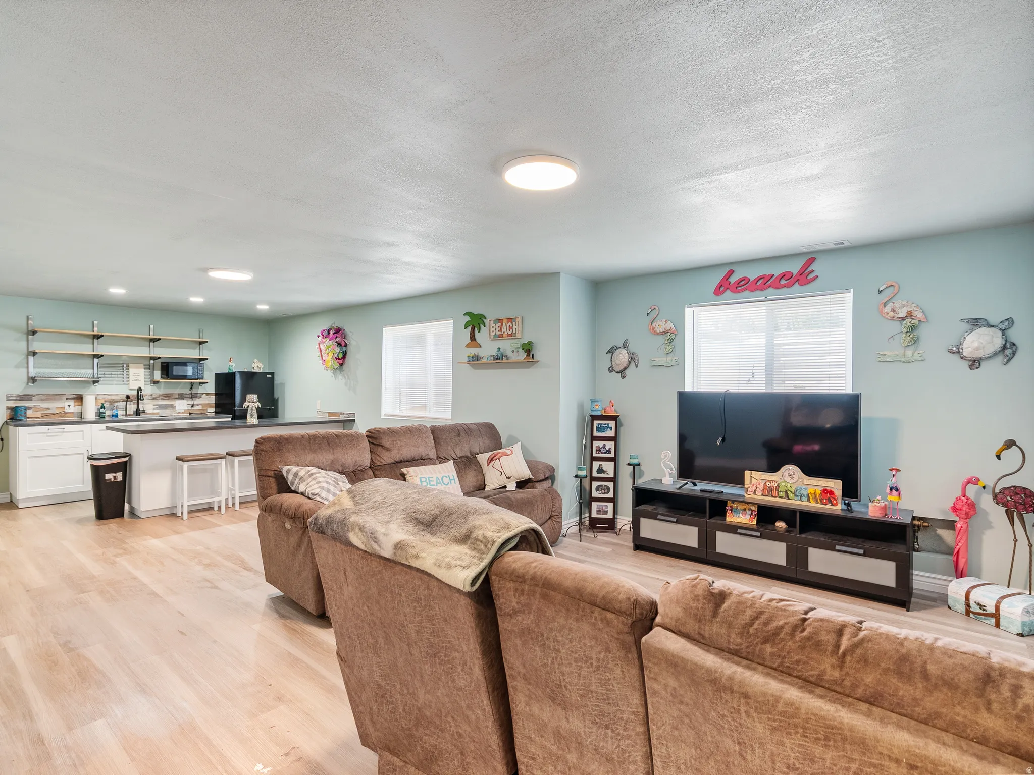 Open-concept living space featuring wood-finish flooring, recessed lighting, and a built-in wet bar with white cabinetry and open shelving