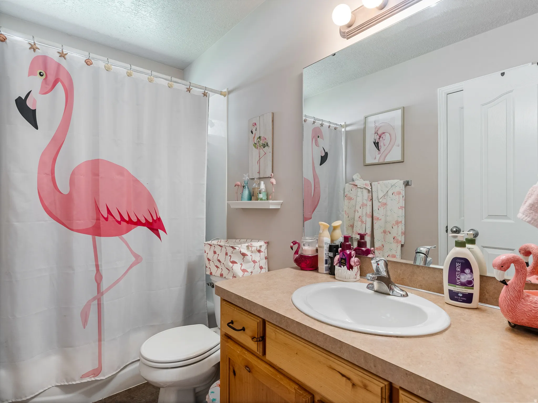 Bathroom featuring a single vanity with a laminate countertop, an oval undermount sink, and wood-finish cabinetry