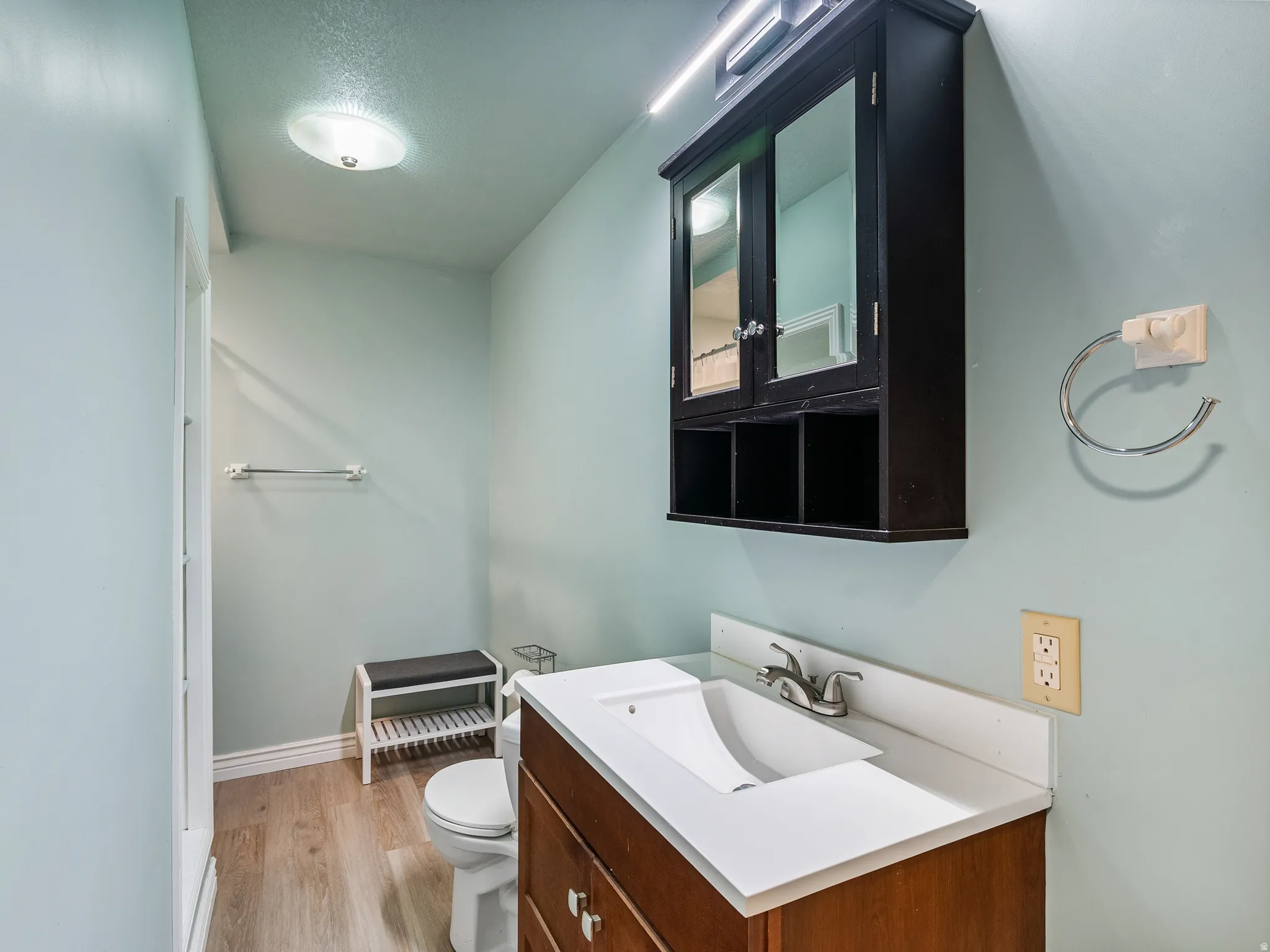Bathroom featuring a wood-finish vanity with an integrated sink and chrome faucet, complemented by a wall-mounted mirrored medicine cabinet
