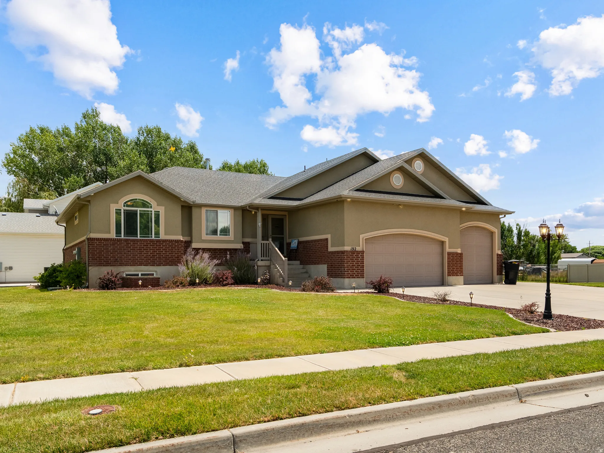 Stucco and brick exterior with a large arched window and a covered entry porch