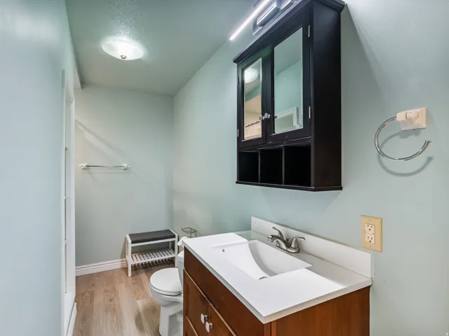 Bathroom featuring a wood-finish vanity with an integrated sink and chrome faucet, complemented by a wall-mounted mirrored medicine cabinet