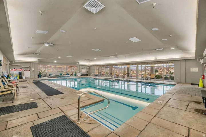 Indoor swimming pool featuring a tiled surround and integrated handrails