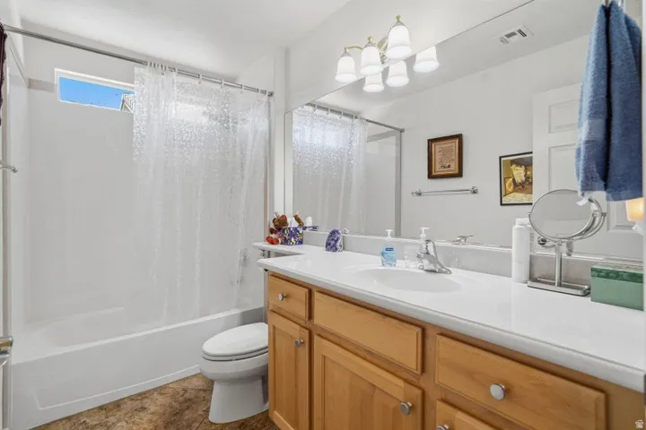 Bathroom featuring a light wood-finish vanity with a white countertop and integrated sink, a large wall-mounted mirror, and a full shower/tub combination with an overhead transom window