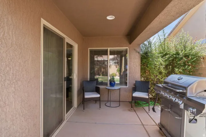 Covered patio featuring textured stucco walls, concrete flooring, a sliding glass door, and a recessed ceiling light