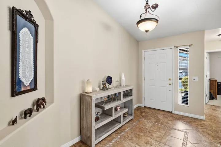 Entryway featuring a white paneled door, a vertical window with blinds, and a decorative overhead light fixture