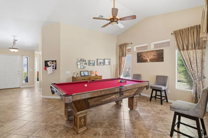 Expansive room featuring vaulted ceilings, ceiling fan, and large tile flooring