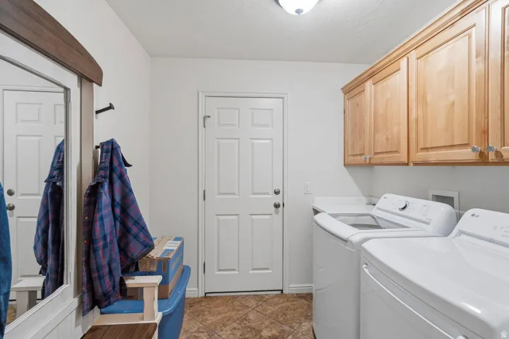 Dedicated laundry area featuring a built-in counter, upper wood cabinetry, and tiled flooring