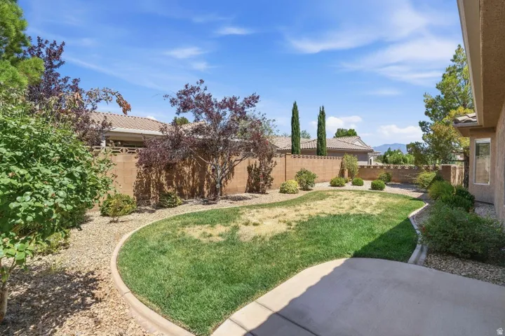 Spacious backyard featuring a curved concrete patio, a grass lawn, and a gravel perimeter