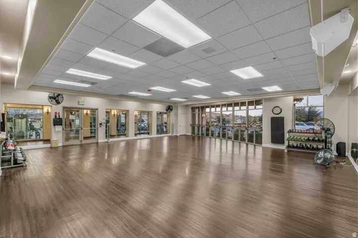 Spacious studio room featuring wood-finish flooring, a full wall of mirrors, and large windows