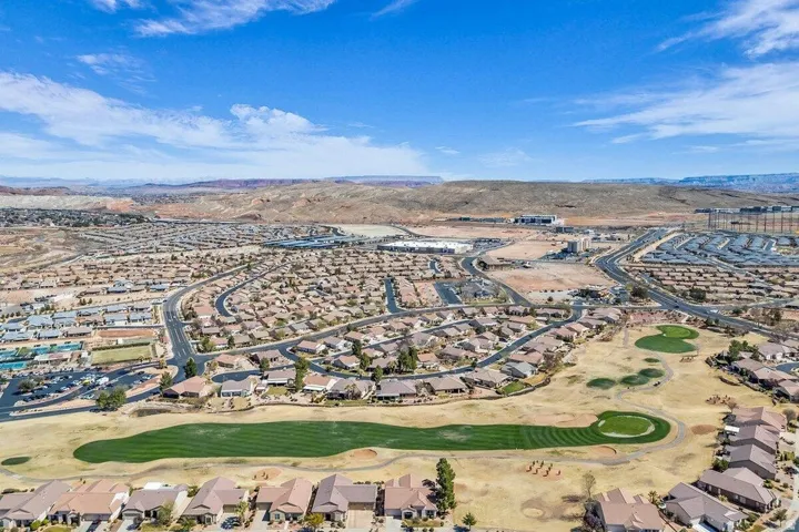Aerial perspective showcasing a residential community with a golf course, mountain backdrop, and varying housing densities