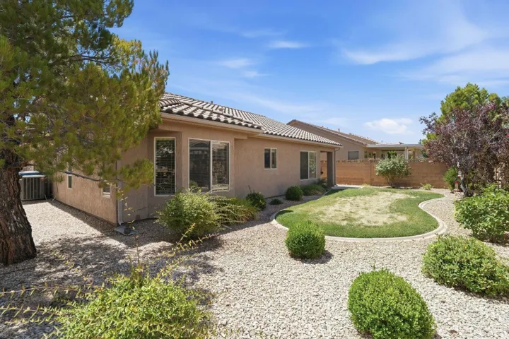 Spacious backyard featuring a shaped lawn area, surrounding gravel landscaping, and mature plantings