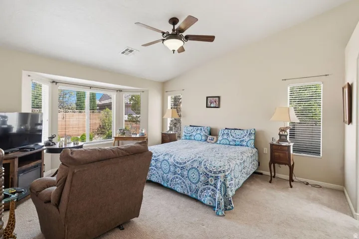 Vaulted ceilings enhance this room featuring a ceiling fan with integrated lighting