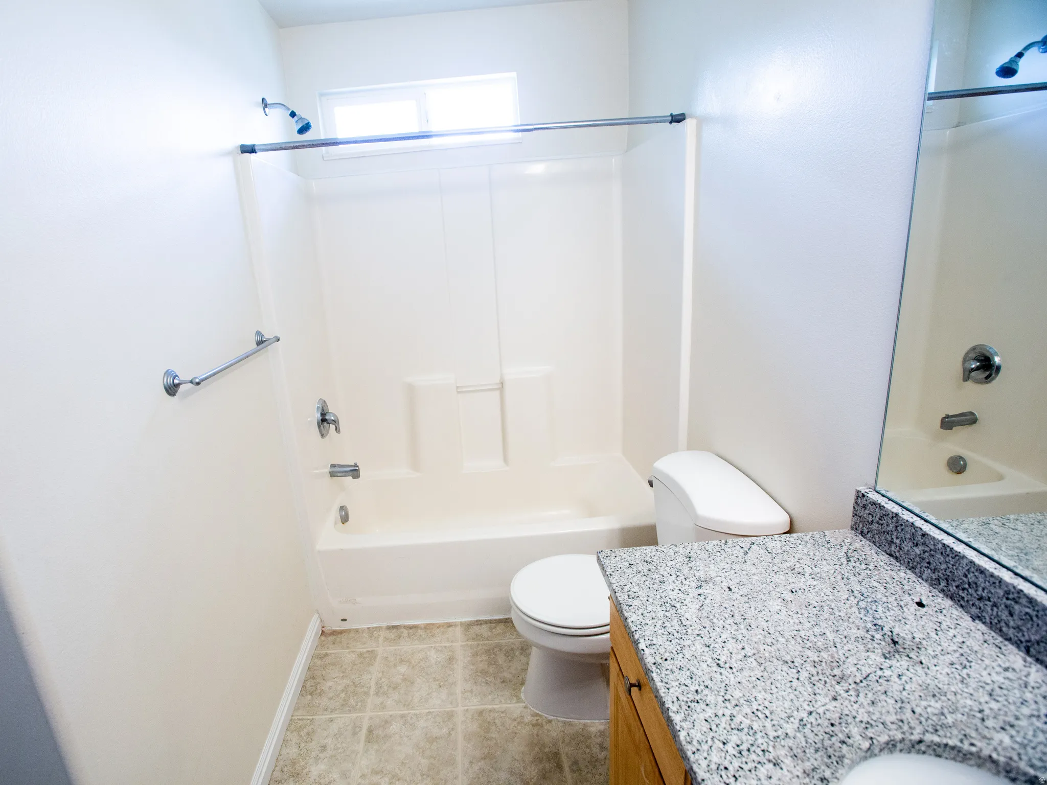 Bathroom featuring a tub/shower combination, a single vanity with a granite-style countertop, and neutral-toned tile flooring