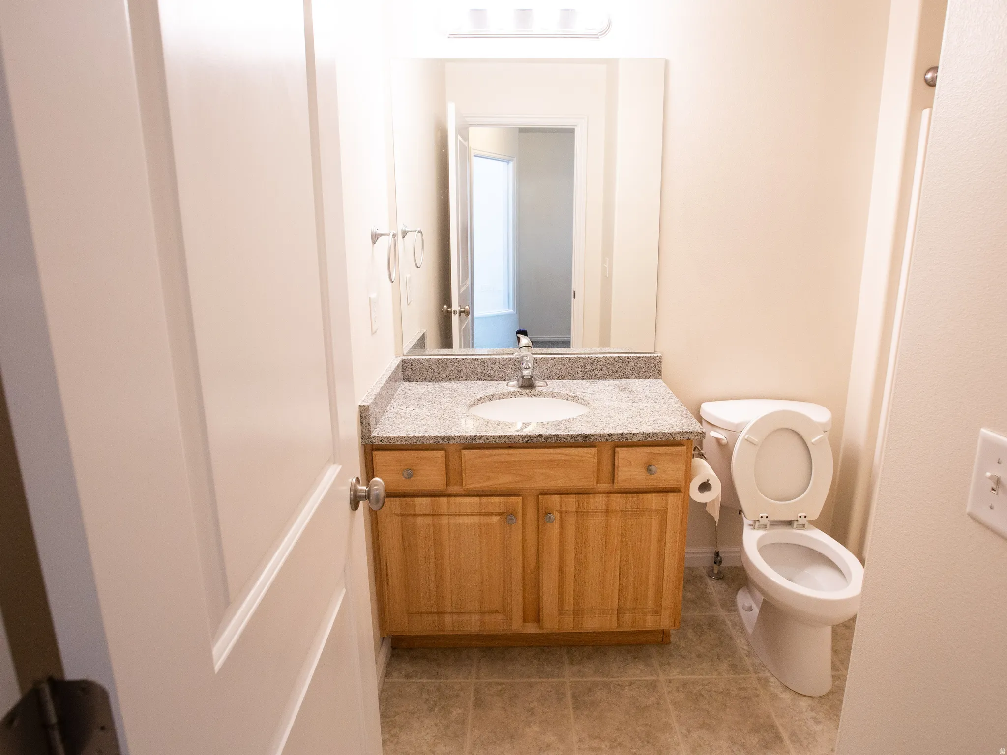 Bathroom featuring a wood vanity with an integrated sink, granite-style countertop, and tile flooring