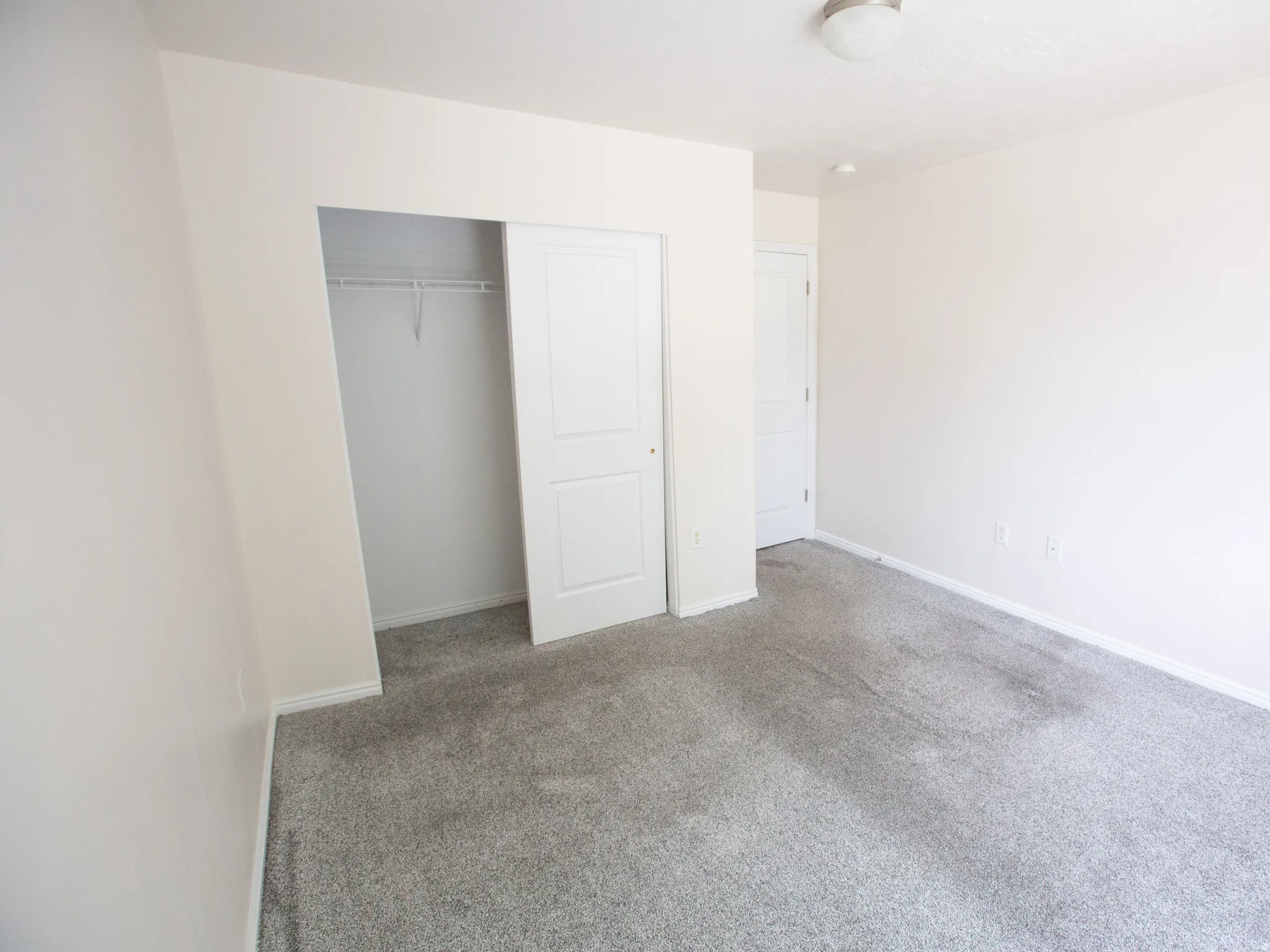Interior room featuring neutral wall paint, light gray carpeting, and a flush mount ceiling light