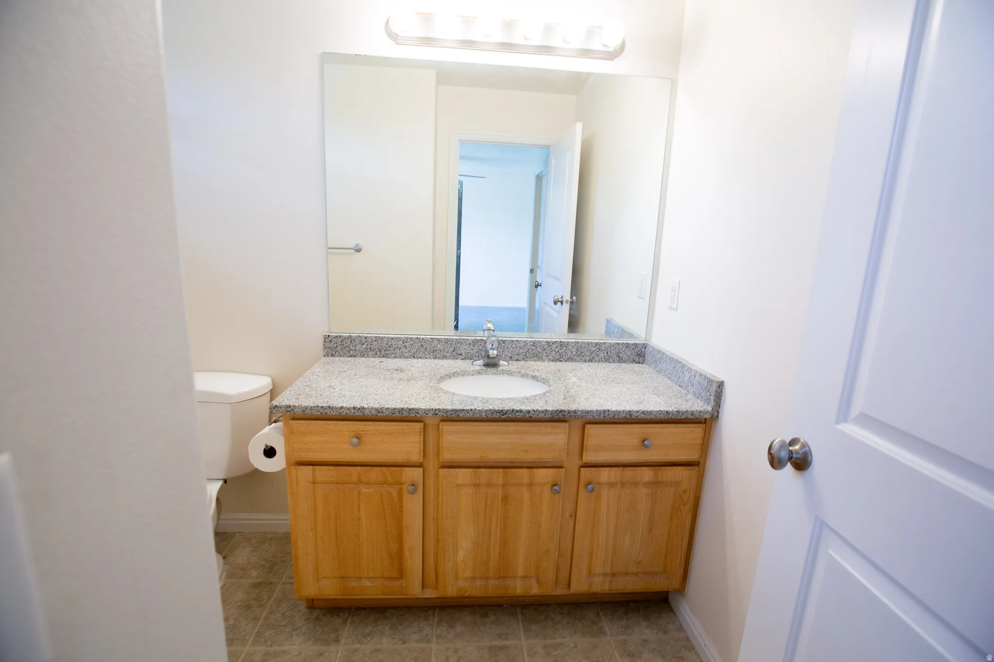 Bathroom vanity with a granite-style countertop, integrated sink, and a wood-finish cabinet with storage
