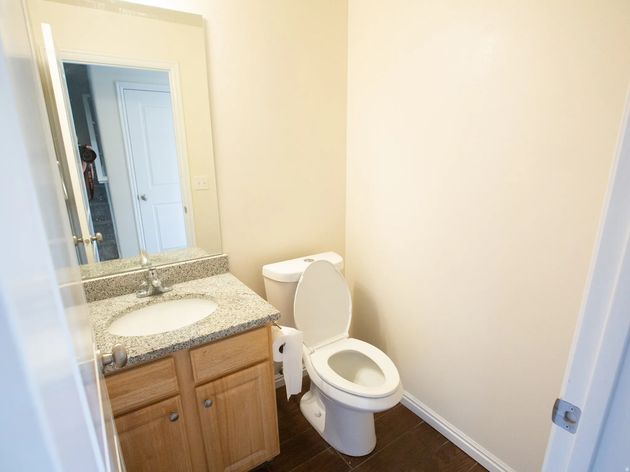 Bathroom vanity featuring a light wood-finish cabinet with silver-tone hardware, an undermount sink, and a speckled countertop