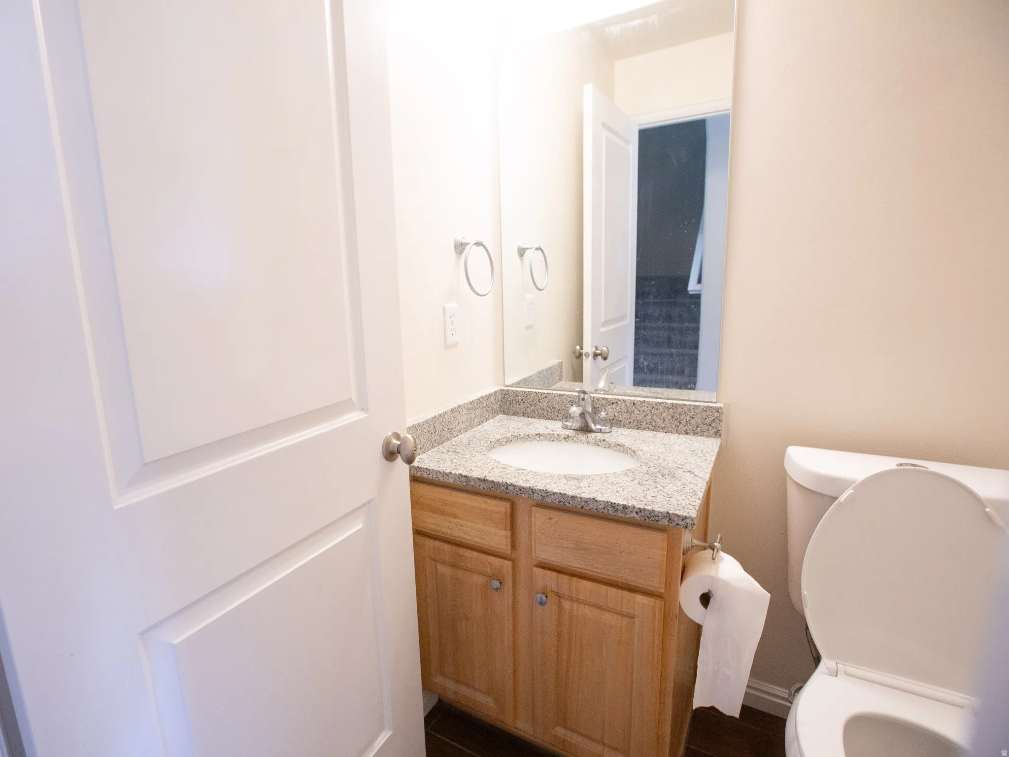 Bathroom vanity featuring a granite-style countertop, undermount sink, and wood-finish cabinetry