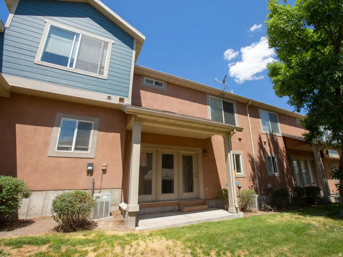 Rear exterior featuring a covered patio, double glass doors, and a stucco finish