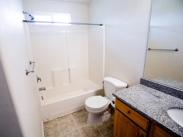 Bathroom featuring a single vanity with a speckled countertop, integrated sink, and wood-finish cabinetry