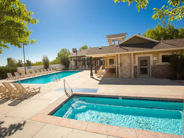 Outdoor aquatic area featuring a swimming pool, a separate spa, and surrounding concrete decking
