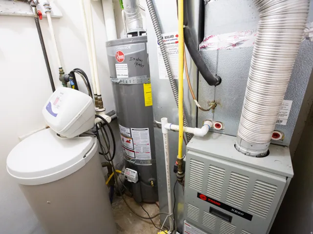 Dedicated utility area featuring a water heater, water softener system, and furnace