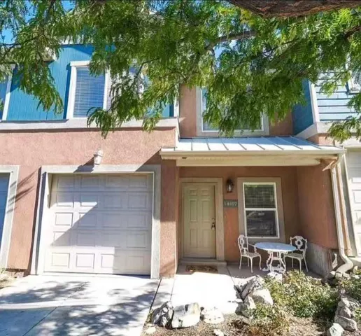 Stucco exterior with a peaked metal awning, an attached garage, and a front entry door with a window
