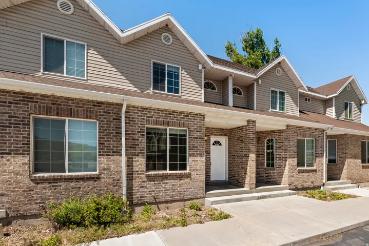 Multi-unit dwelling featuring brick and siding facade, multiple gabled rooflines, covered entryways, and white-framed windows