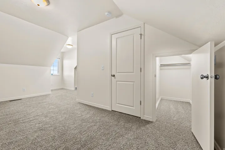 Carpeted room with a partial sloped ceiling and white painted walls